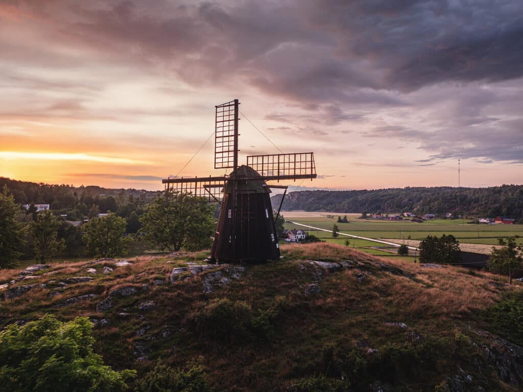 Gammal väderkvarn på kulle vid solnedgång, flygfoto taget med drönare i Stordal på Tjörn