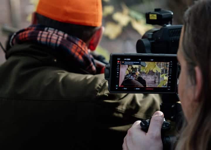 Kamerans monitor visar tagningen under produktfilmning av Inuheats Heat Ready-system: närbild på uppvärmda handskar, filmat i höstskog